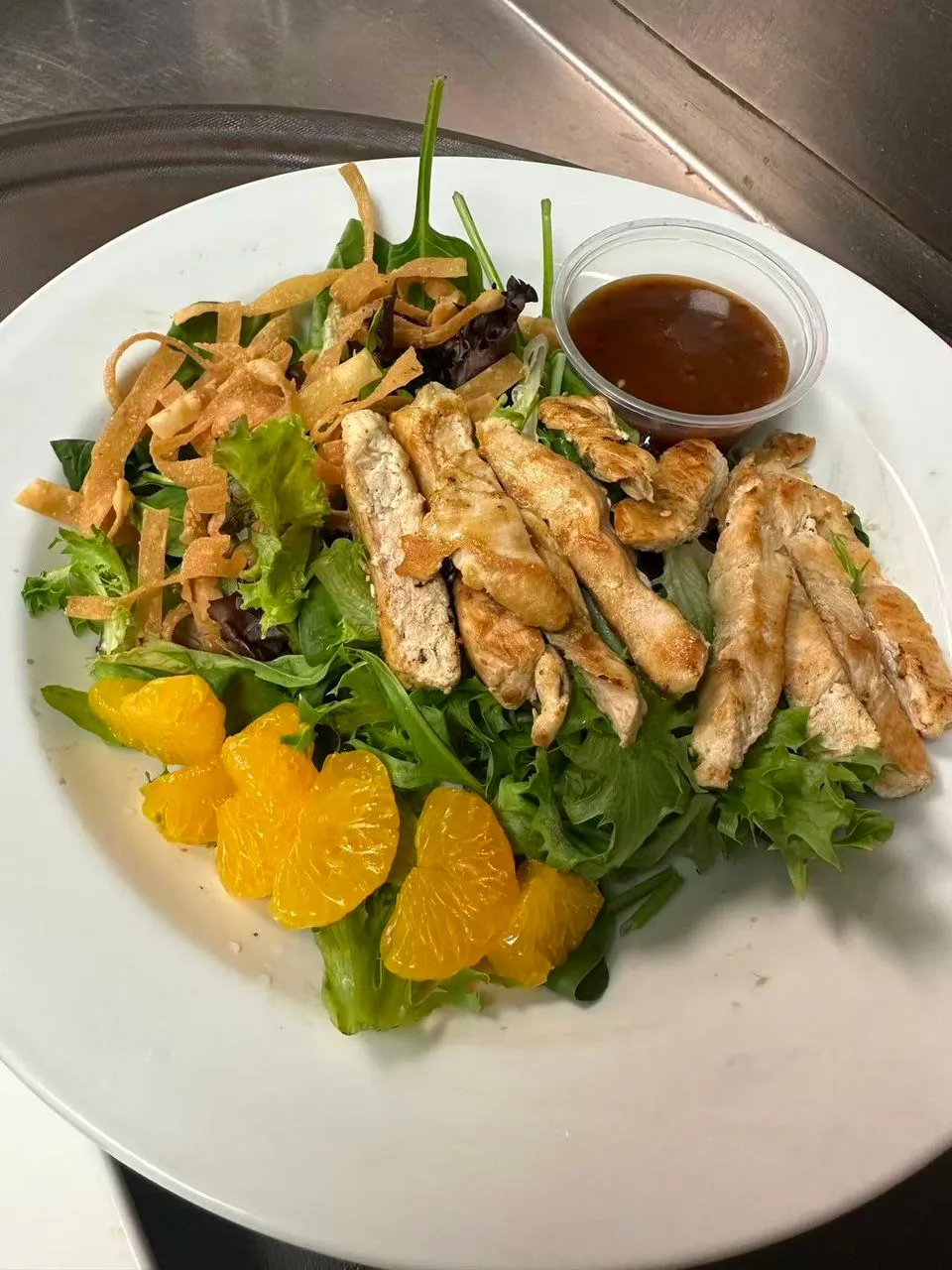 Chicken salad with oranges, crispy wontons, and dressing on a plate